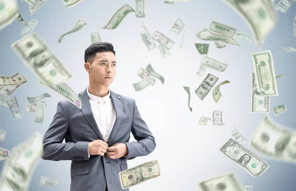 Серьезный азиатский бизнесмен и долларовый дождь — стоковое фото