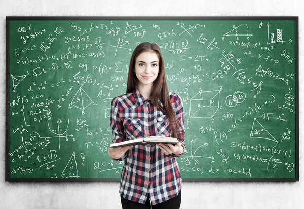 Teen girl with book near blackboard, formulas