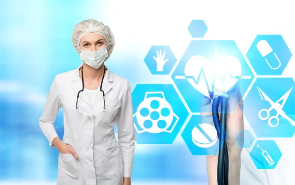 Mujer médico en una máscara y los iconos médicos de la mano — Foto de Stock