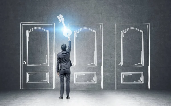 Podnikatel, drží obří klíč poblíž nakreslené dveře — Stock fotografie