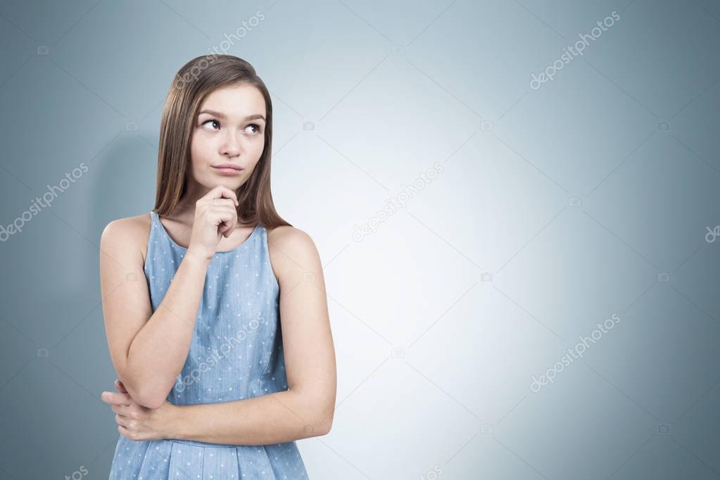 Pretty young woman in a blue dress thinking