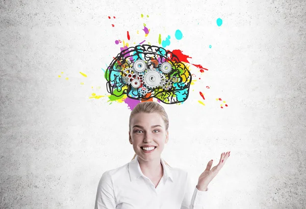 Smiling blond woman showing brain with cogs — Stock Photo, Image