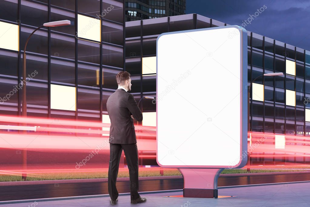 Pensive bearded businessman looking at billboard