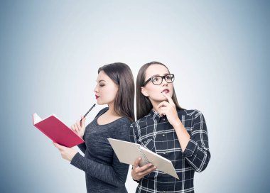 Kitaplar, gri duvar ile iki kız öğrenci