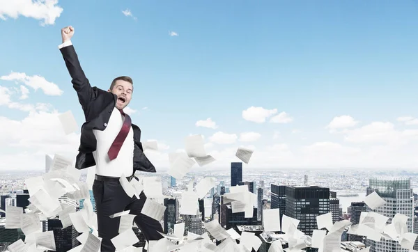 Blond businessman jumping, cityscape, papers — Stock Photo, Image