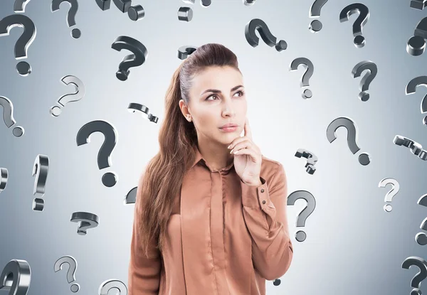 Pensive woman in brown, question marks — Stock Photo, Image