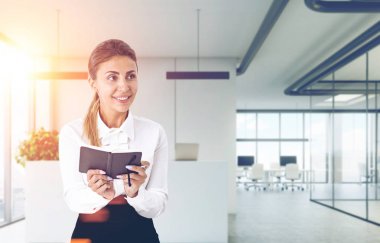 Bir ofiste bir planer ile gülümseyen kız tonda