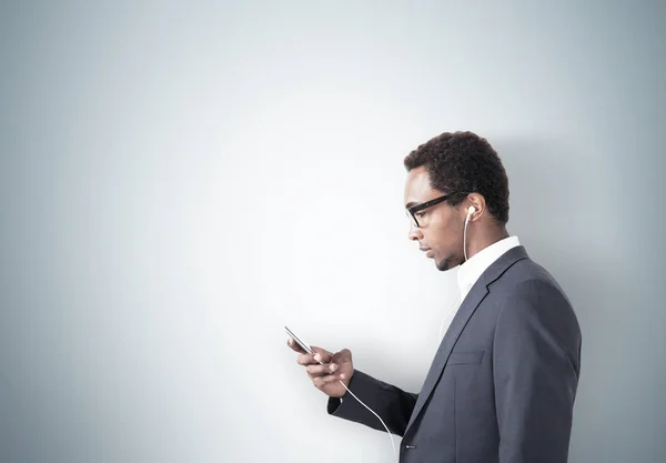 African American man with a smartphone, gray wall — Stock Photo, Image