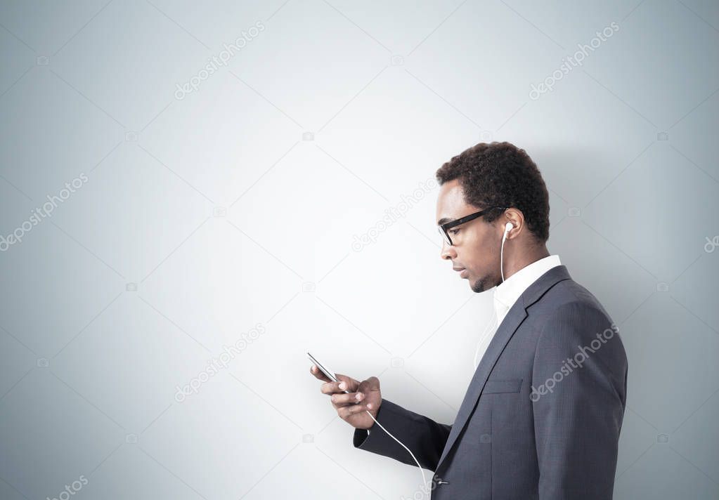 African American man with a smartphone, gray wall