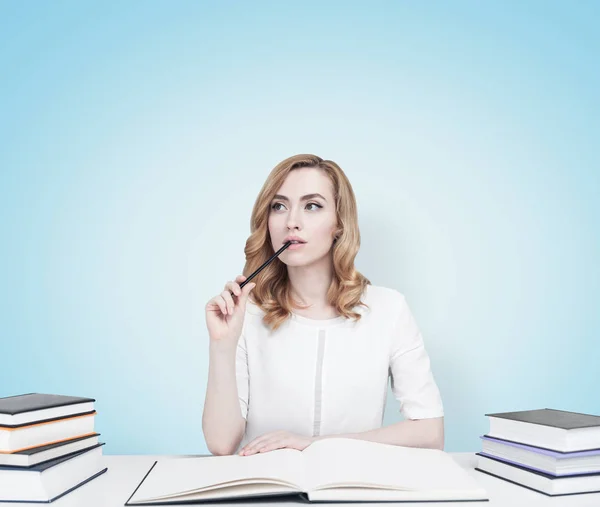 Rothaarige Studentin an einem Tisch mit Büchern, blau — Stockfoto