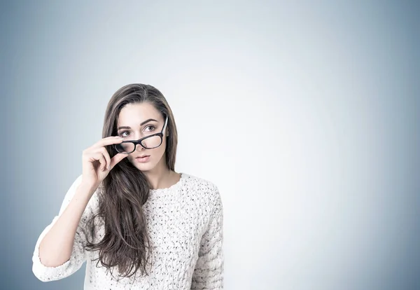 Mujer joven en suéter quitándose las gafas, gris — Foto de Stock