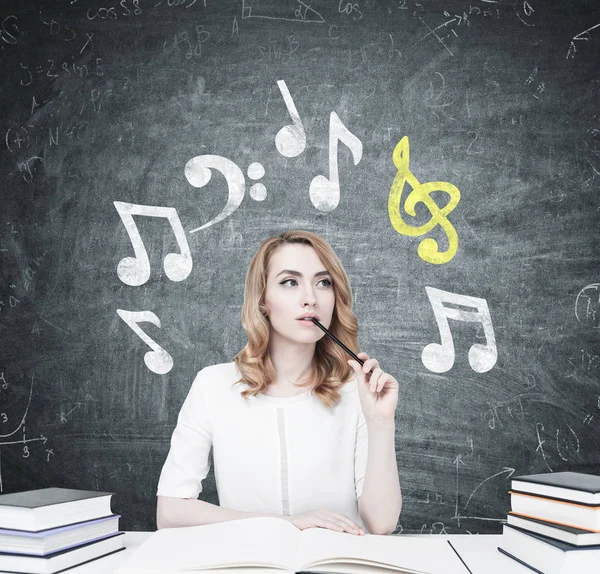 Étudiant roux à une table, notes de musique — Photo