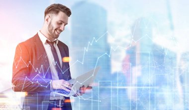 İşadamı ile bir laptop mavi bir şehirde, grafikler