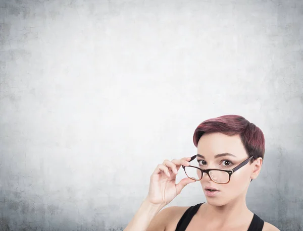 Femme surprise enlevant des lunettes, du béton — Photo