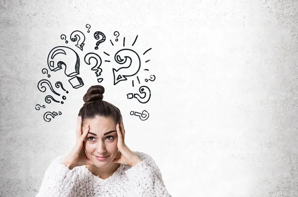 Stressed young woman with a bun, question marks — Stock Photo, Image