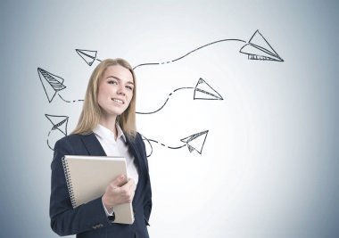 Defter, kağıt uçaklar ile gülümseyen iş kadını