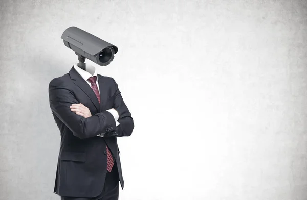 Porträt eines Geschäftsmannes im Anzug und mit verschränkten Armen. Sein Kopf ist eine Videokamera. Konzept der Überwachung und Überwachung. Hintergrund einer Betonmauer. Attrappe — Stockbild Mann mit Kamerakopf, Beton — Stockfoto
