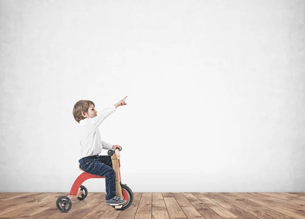 Sevimli çocuk parmak oda gösterilen bir üç tekerlekli bisiklet üzerinde — Stok fotoğraf