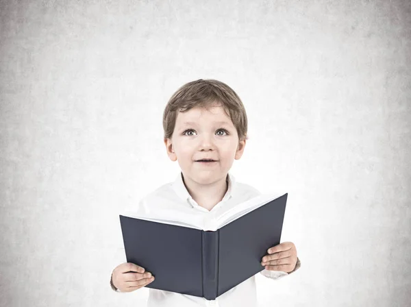 Söt liten pojke med en bok, betong — Stockfoto