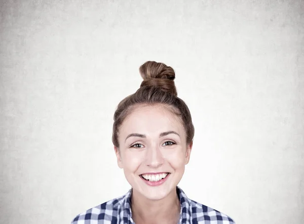 Jeune femme souriante avec un chignon, béton — Photo