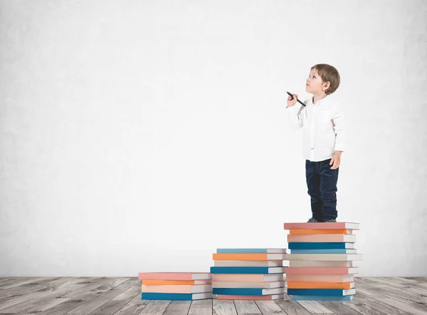 Söt liten pojke med en markör på böcker högen — Stockfoto