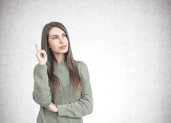 Mujer reflexiva en verde apuntando hacia arriba, hormigón — Foto de Stock