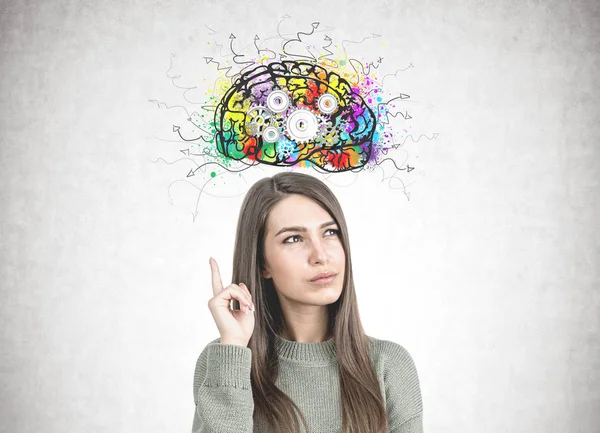 Mujer pensativa en verde apuntando hacia arriba, cerebro engranaje — Foto de Stock