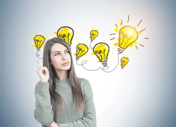 Mujer pensativa en verde apuntando hacia arriba, lluvia de ideas — Foto de Stock