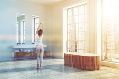 Loft banyo köşesi bir ahşap zemin, beyaz duvarlar ve bir çift lavabo ile iki dar dikey ayna üstünde asılı. Ahşap küvet. Bir kadın 3d render resim tonda