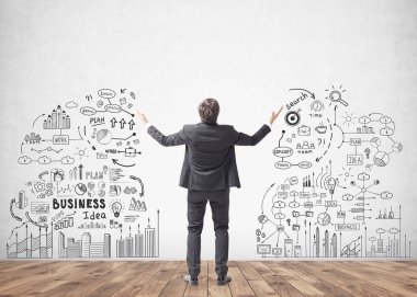 Arkadan görünüş genç başarılı işadamı ile ayakta eller havaya bir iş zaferini kutluyor. Beton duvar ile bir iş stratejisi kroki