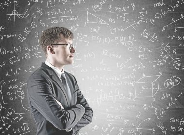 Kendine güvenen genç işadamı yan görünüm bir takım elbise ve gözlük ve ile ayakta silah mesafe içine bakarak geçti. Blackboard arka plan üzerine bir fizik formülleri ile.