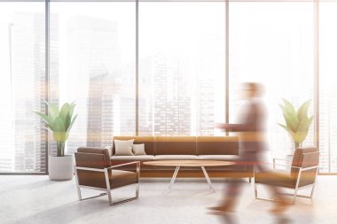 Man walking in panoramic lounge with brown sofa