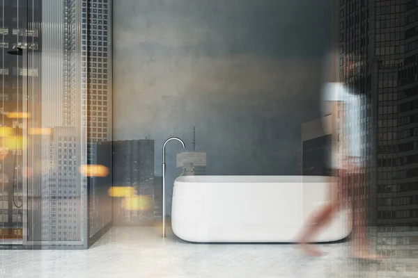 Mujer caminando en baño gris con ducha y bañera —  Fotos de Stock