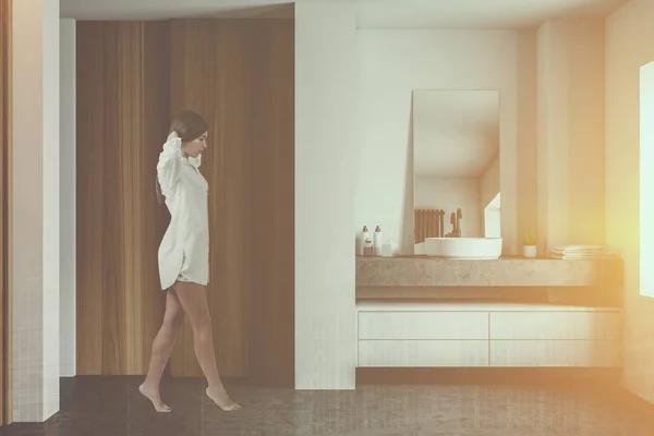 Žena kráčející v bílé a dřevěné koupelně s dřezem — Stock fotografie