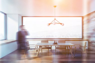 Beyaz ve ahşap yemek odasında yürüyen bir adam