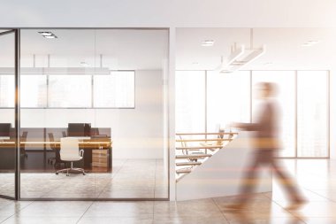 Beyaz ofiste yürüyen bir iş adamı.