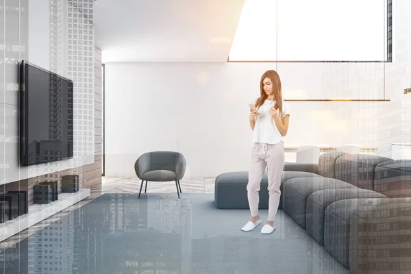 Woman in white living room with TV — ストック写真
