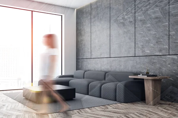 Mulher andando na sala de estar de concreto com sofá — Fotografia de Stock