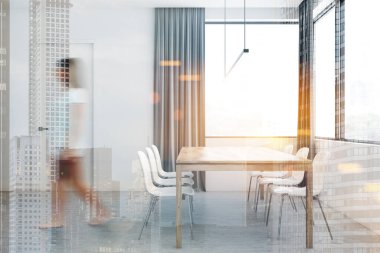 Beyaz perdeli bir kadın yemek odasında yürüyor.