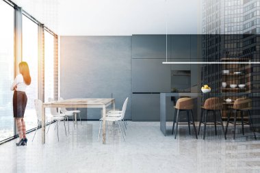 Barlı ve masalı gri mutfakta bir kadın.