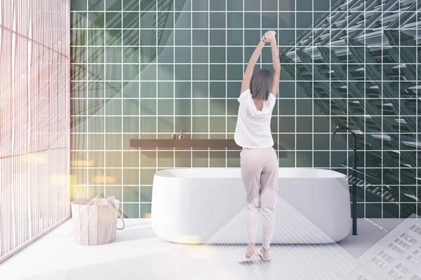 Женщина в зеленой плитке ванная комната с ванной — стоковое фото