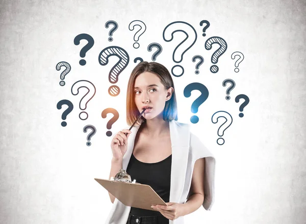 Thoughtful woman with clipboard, question marks — Stock Photo, Image