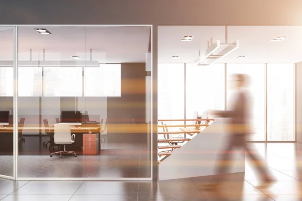 Businessman walking in gray office with reception — Stock Photo, Image