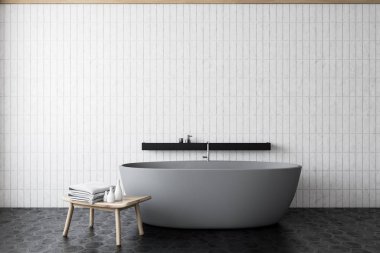 Gri küveti ve sandalyesi olan beyaz fayanslı banyo.