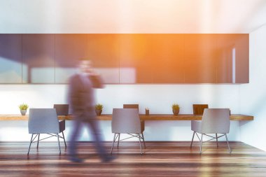 Beyaz açık uzay ofisinde yürüyen bir iş adamı