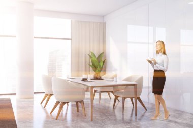 Beyaz yemek odasındaki koltuklu kadın.