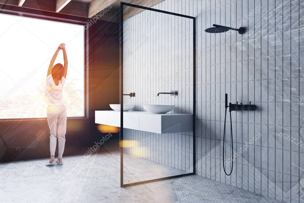 Woman in gray bathroom with sink and shower