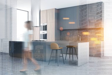 Gri mutfak köşesinde bar sahibi bir kadın.