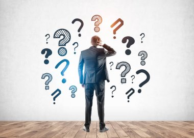 Kafası karışmış işadamı soru işaretlerine bakıyor.