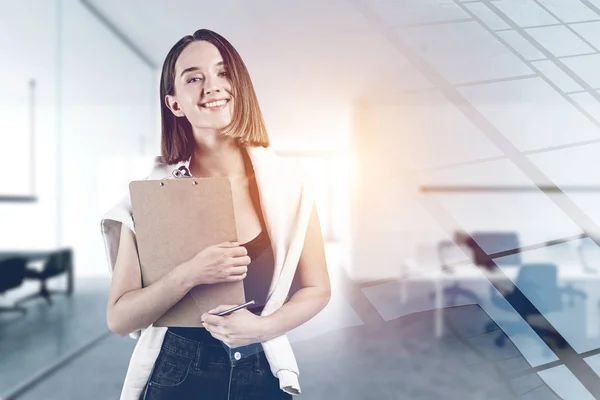 Smiling young woman with clipboard in office